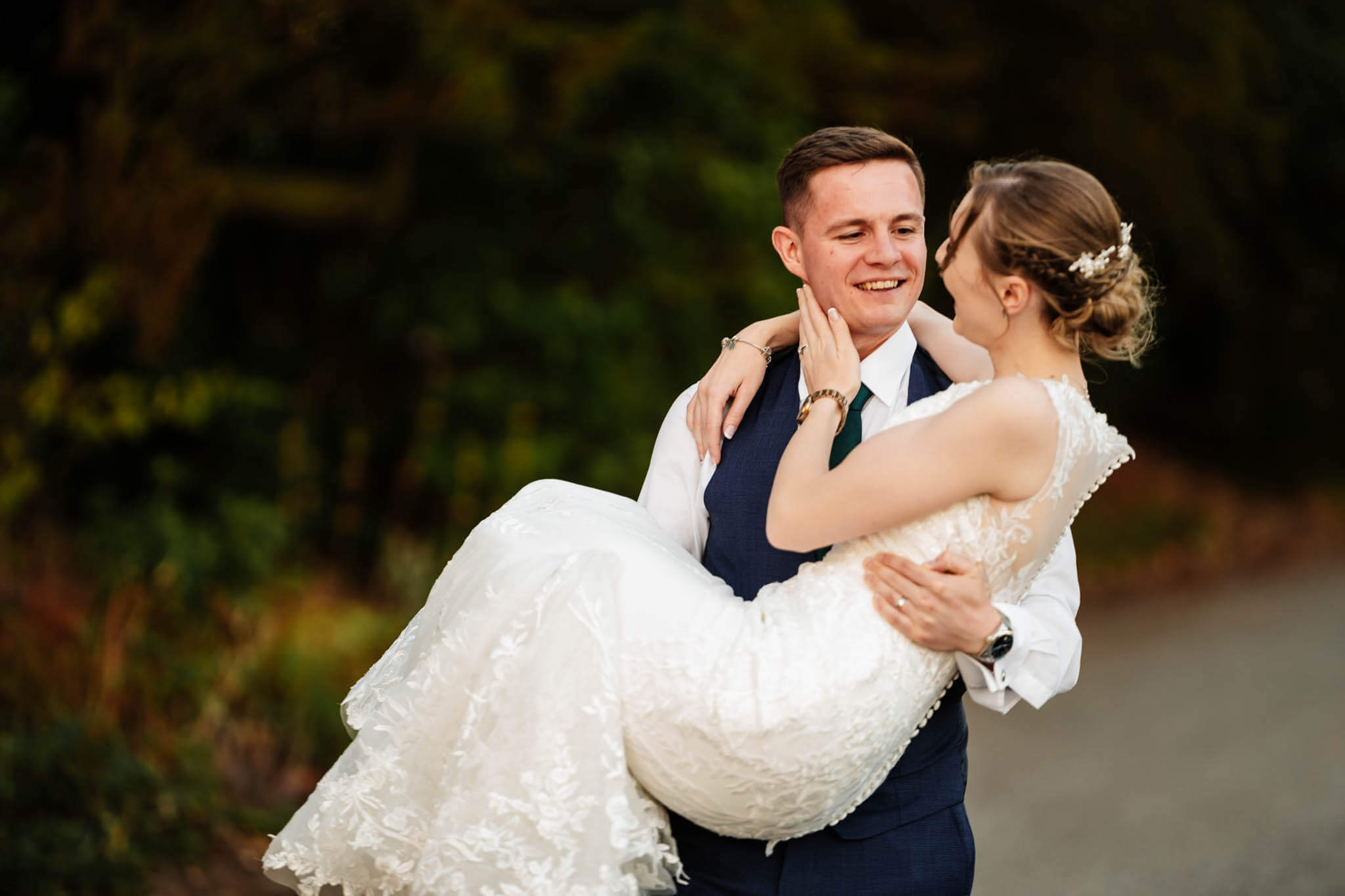 Bride is being carried by the groom down the drive way at Dovecliff Hall Hotel