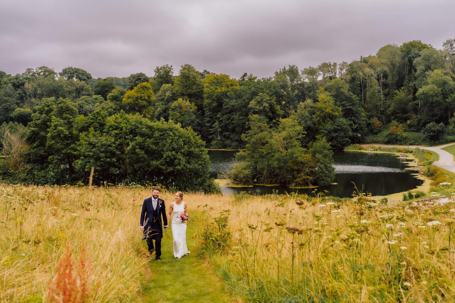 Bride and groom walk back up the hill towards Ashley Wood Farm wedding venue in Wiltshire.