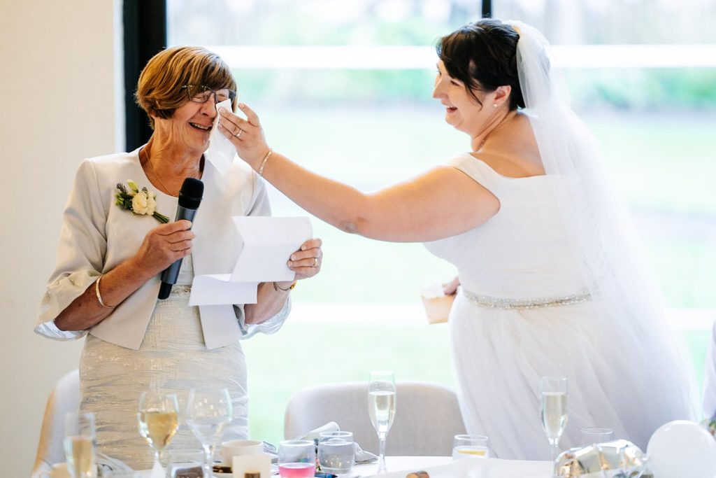 Bride wipes away a tear from her mother's eye during a particularly emotional speech
