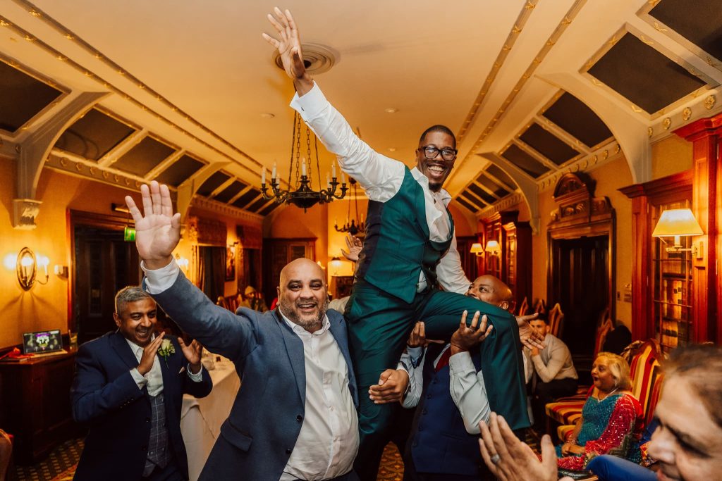 Groom is lifted up by his friends during the party at Kilworth House