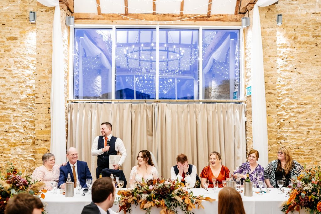 Bestman laughs whilst the groom holds his head in his hands after the joke the best man made