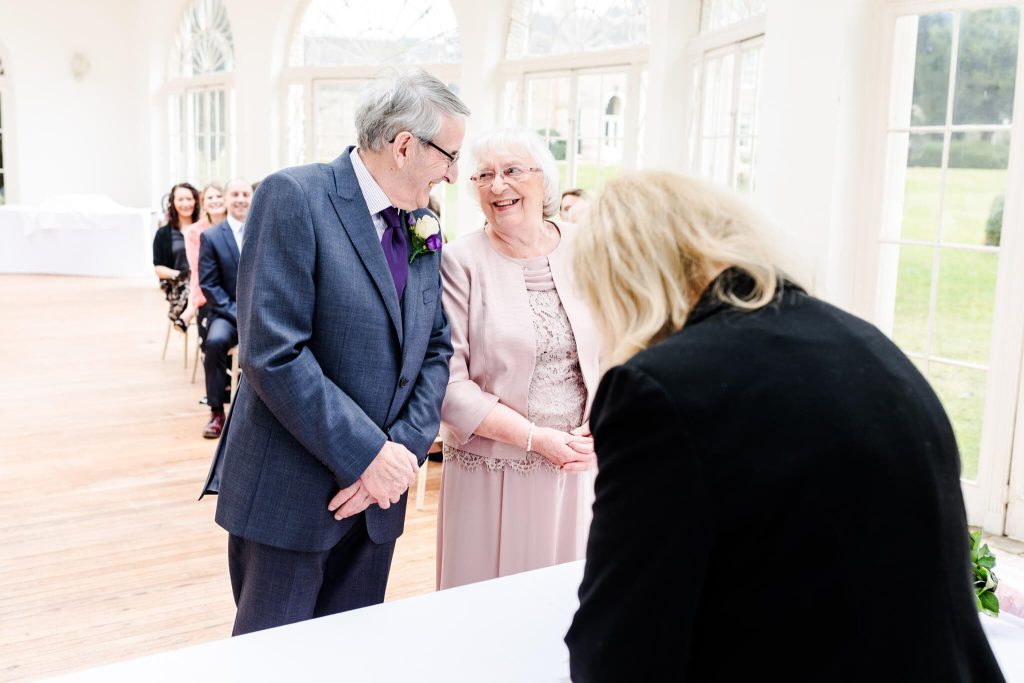 An older bride and groom who are getting married after 34 years together give each other a smile during their wedding ceremony at Barton Hall in Northamptonshire