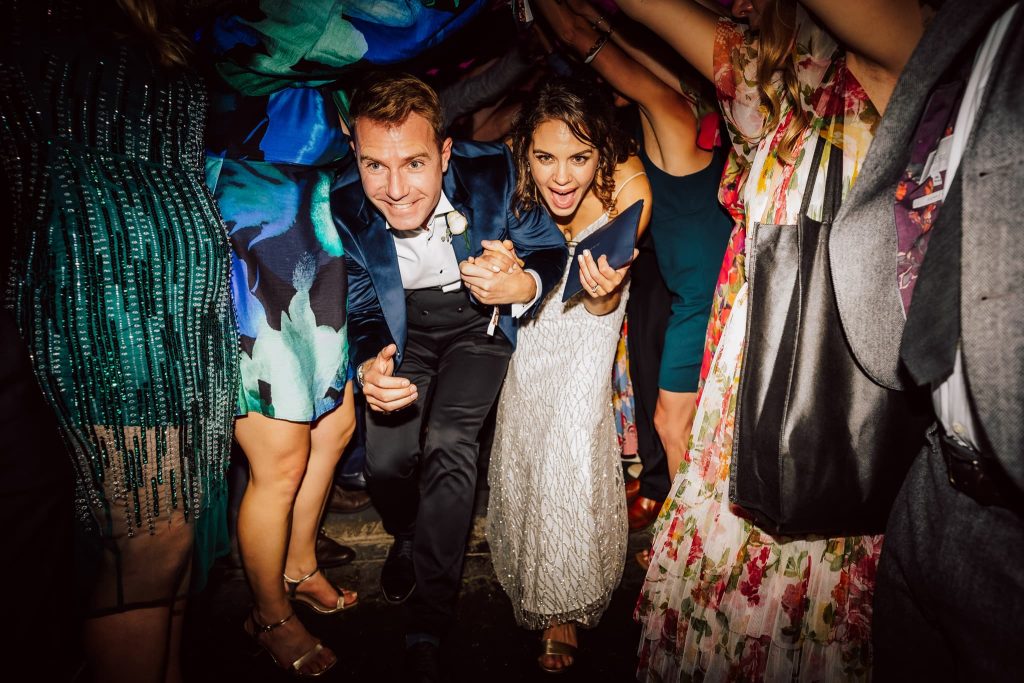 Bride and groom stoop down and run through a tunnel made by their guests at the end of their London wedding in Windsor