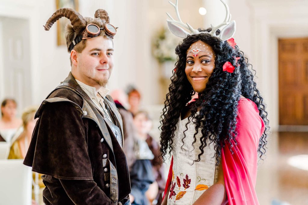Bride and groom hold hands and smile, dressed in Dungeons & Dragon themed costumed during their ceremony at Colwick Hall